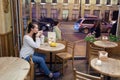 Young attractive girl sitting in the evening in a cafe with a Cup of tea to the backdrop of passing cars and city life. She looks Royalty Free Stock Photo