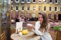 Young attractive girl sitting in the evening in a cafe with a Cup of tea to the backdrop of passing cars and city life. She looks Royalty Free Stock Photo