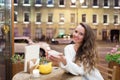 Young attractive girl sitting in the evening in a cafe with a Cup of tea to the backdrop of passing cars and city life. She looks Royalty Free Stock Photo