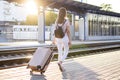 Attractive girl is standing with luggage at the station and waiting for the train, the student is going on a trip, she is walking Royalty Free Stock Photo