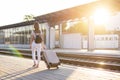 Attractive girl is standing with luggage at the station and waiting for the train, the student is going on a trip, she is walking Royalty Free Stock Photo