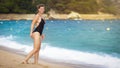 Young attractive girl in swimsuit on beach. Seaside vacation. beautiful woman is walking along beach Royalty Free Stock Photo