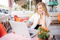 Young attractive girl talking on mobile phone and smiling while sitting alone in coffee shop during free time and working on table Royalty Free Stock Photo