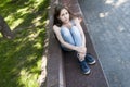 Young attractive girl waiting a call sitting on the bench. Summer park. Photo Royalty Free Stock Photo