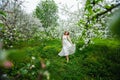 Young attractive girl walks in spring green park enjoying flowering nature. Healthy smiling girl spinning on the spring lawn. Alle