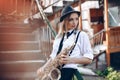 Young attractive girl in white shirt with a saxophone - outdoor in old town. young woman with sax thinking about something