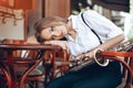 Young attractive girl in white shirt with a saxophone sitting on caffe shop - outdoor in street. young woman with sax looking Royalty Free Stock Photo