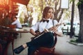 Young attractive girl in white shirt with a saxophone sitting near caffe shop - outdoor in sity. young woman with sax thinkin Royalty Free Stock Photo