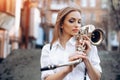 Young attractive girl in white shirt with a saxophone standing in street - outdoor. young woman with sax thinking about somet