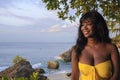 Glamorous African American black woman in chic and elegant summer dress posing relaxed on summer sunset beach