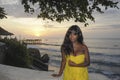 Glamorous African American black woman in chic and elegant summer dress posing relaxed on summer sunset beach