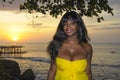 Glamorous African American black woman in chic and elegant summer dress posing relaxed on summer sunset beach