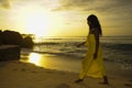 Glamorous African American black woman in chic and elegant summer dress posing relaxed walking on summer sunset beach