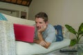 Young attractive handsome happy man lying at home couch working with laptop computer netbook relaxed in internet business concept Royalty Free Stock Photo