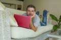 Young attractive and handsome happy man lying at home sofa couch working with laptop computer netbook relaxed in internet business Royalty Free Stock Photo
