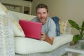 Young attractive and handsome happy man lying at home sofa couch working with laptop computer netbook relaxed in internet business Royalty Free Stock Photo