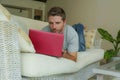 Young attractive and handsome happy man lying at home sofa couch working with laptop computer netbook relaxed in internet business Royalty Free Stock Photo