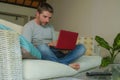 Young attractive and handsome happy man sitting at home sofa couch working with laptop computer netbook relaxed smiling cheerful i Royalty Free Stock Photo