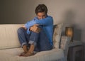 Young attractive and handsome sad latin man sitting tired and depressed at home sofa couch feeling overwhelmed and worried sufferi Royalty Free Stock Photo