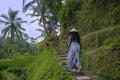 Young attractive happy afro american black woman 30s exploring rice fields forest and jungle in Bali wearing asian hat