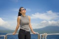 Young attractive and happy Asian Chinese woman on excursion ship or ferry enjoying sea breeze on summer holiday sea boat trip