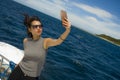 Young attractive and happy Asian Chinese woman selfie portrait picture with mobile phone on boat or ferry smiling with blue sea ba Royalty Free Stock Photo