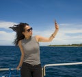 Young attractive and happy Asian Chinese woman selfie portrait picture with mobile phone on boat or ferry smiling with blue sea ba Royalty Free Stock Photo