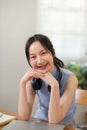 Young attractive happy asian female student sitting at living room floor smiling and looking up at camera working on Royalty Free Stock Photo