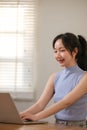 Young attractive happy Asian female student sitting in the living room smiling and looking at the camera while working Royalty Free Stock Photo