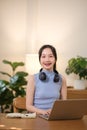 Young attractive happy Asian female student sitting in the living room smiling and looking at the camera while working Royalty Free Stock Photo