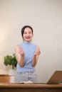 Young attractive happy Asian female student standing in the living room smiling and looking at the camera while working Royalty Free Stock Photo