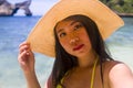 Young attractive and happy Asian Korean woman in pamela Summer hat and yellow bikini taking selfie with phone at beautiful beach Royalty Free Stock Photo