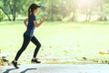 Young attractive happy asian runner woman running in public nature city park wearing sporty sportswear with copy space and sun lig Royalty Free Stock Photo