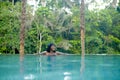Young attractive happy black African American woman enjoying holidays in tropical resort infinity pool to beautiful jungle landsca Royalty Free Stock Photo
