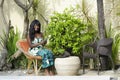 Happy black afro american woman in elegant dress working on luxury terrace villa with laptop and mobile phone Royalty Free Stock Photo