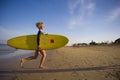 Young attractive and happy blonde surfer girl in beautiful beach carrying yellow surf board running out of the sea enjoying summer Royalty Free Stock Photo