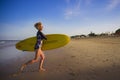 Young attractive and happy blonde surfer girl in beautiful beach carrying yellow surf board running out of the sea enjoying summer Royalty Free Stock Photo