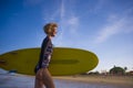 Young attractive and happy blonde surfer girl in beautiful beach carrying yellow surf board walking out of the sea enjoying summer Royalty Free Stock Photo