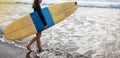 Young attractive and happy surfer girl in beautiful beach carrying yellow surf board walking in the ocean enjoying Royalty Free Stock Photo