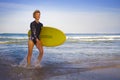 Young attractive and happy blonde surfer girl in beautiful beach carrying yellow surf board walking out of the water enjoying summ Royalty Free Stock Photo