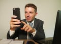 Young attractive and happy businessman in suit and necktie working on office laptop computer desk using mobile phone on isolated Royalty Free Stock Photo