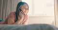 Young attractive happy caucasian woman lying on bed and speaking phone at home in morning