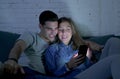 Young attractive and happy couple using internet app on mobile phone enjoying and laughing together sitting at home living room so Royalty Free Stock Photo