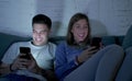 Young attractive and happy couple using internet app on mobile phone enjoying and laughing together sitting at home living room so Royalty Free Stock Photo