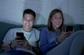 Young attractive and happy couple using internet app on mobile phone enjoying and laughing together sitting at home living room so Royalty Free Stock Photo