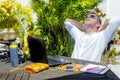 Young attractive and happy digital nomad man working outdoors from coffee shop with laptop computer leaning back relaxed and confi Royalty Free Stock Photo