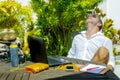 Young attractive and happy digital nomad man working outdoors from coffee shop with laptop computer leaning back relaxed and confi Royalty Free Stock Photo
