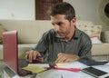 Young attractive and happy freelance business man with calculator and laptop doing domestic accounting paperwork of domestic Royalty Free Stock Photo