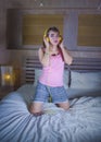 Young attractive and happy girl in bed with yellow headphones listening to music on internet with mobile phone dancing and singing Royalty Free Stock Photo