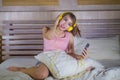 Young attractive and happy girl in bed with yellow headphones listening to music on internet with mobile phone dancing and singing Royalty Free Stock Photo